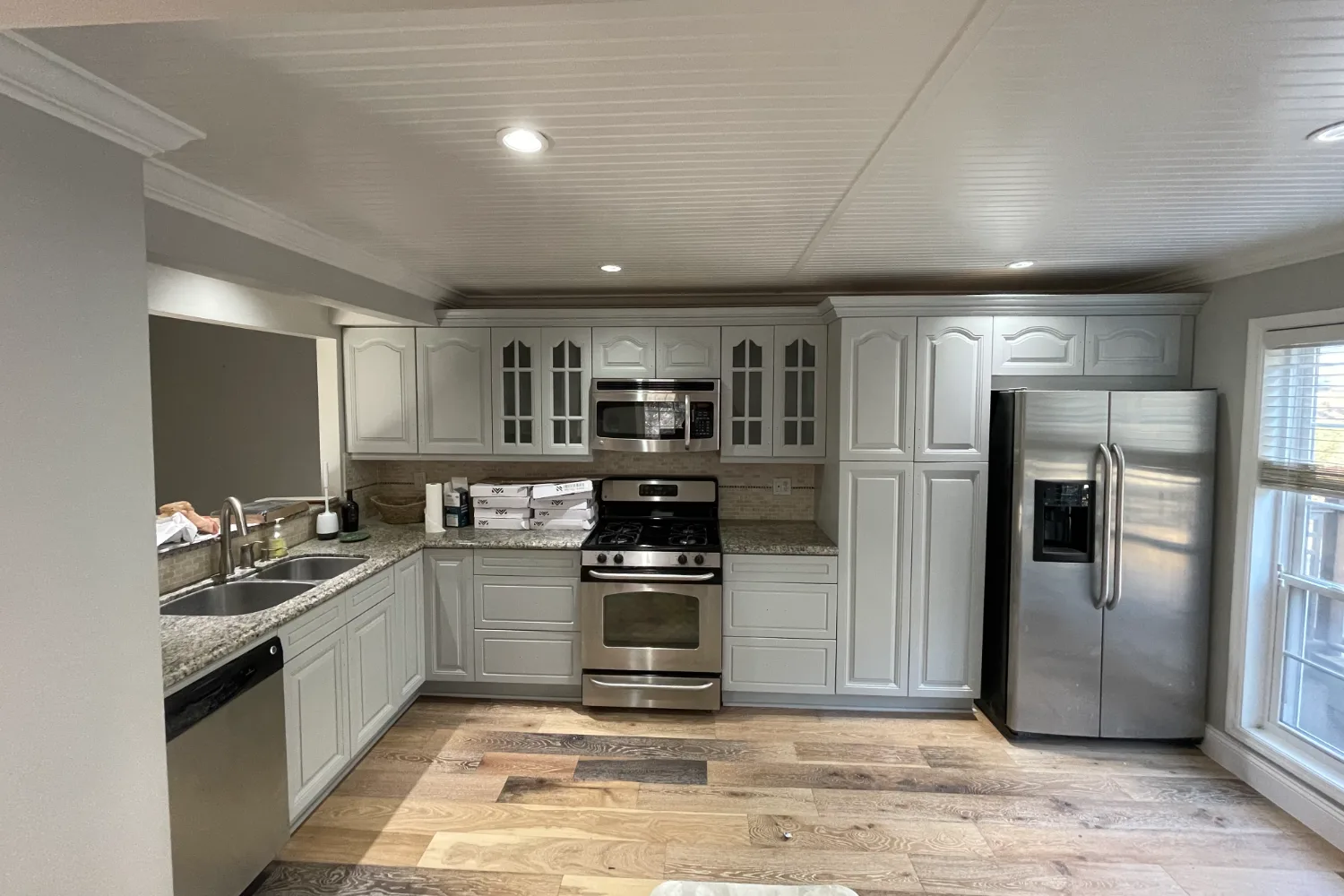 The same kitchen after refinishing, cabinets in a soft gray finish