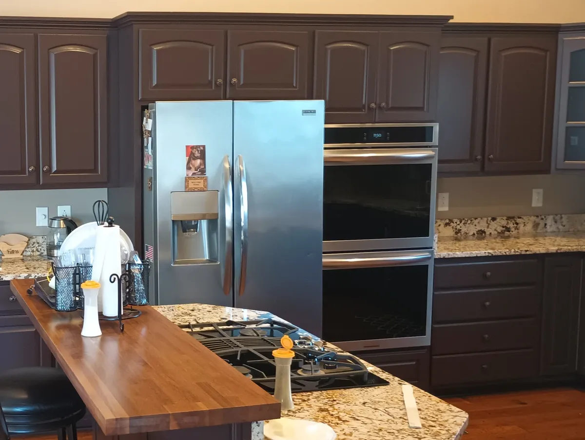 Kitchen cabinets refinished in a deep espresso brown with granite counters